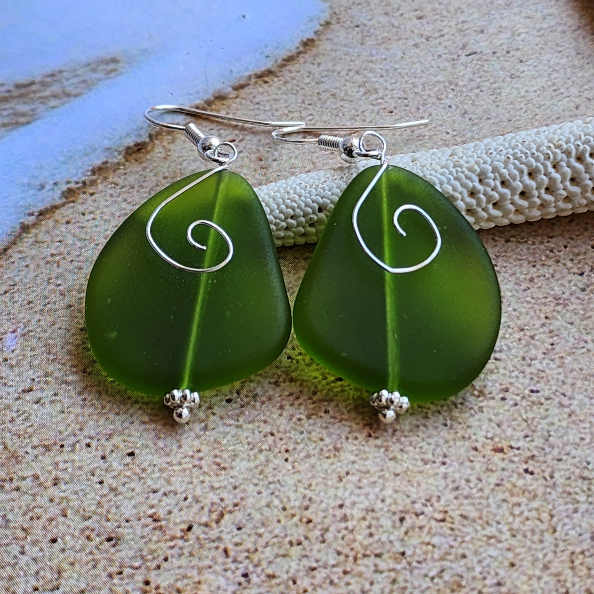 Green sea glass dangle earrings with decorative wire detailing and hook ear wires.